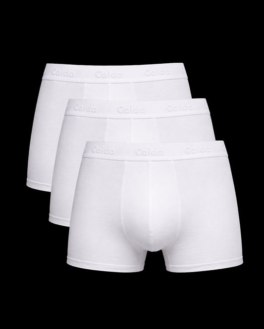 Three pairs of white boxer briefs on a black background